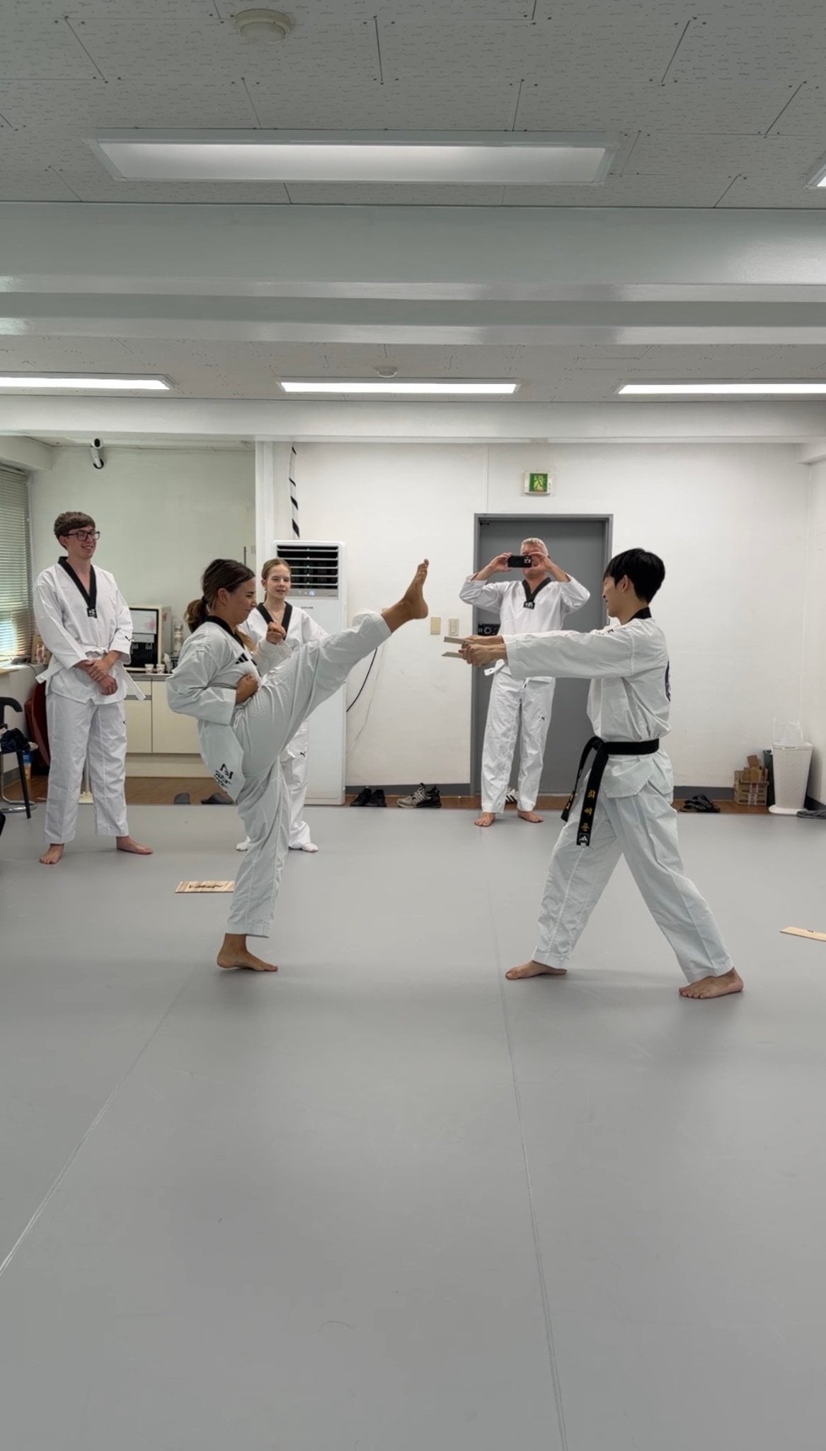 Students practicing a kick with an instructor at Blue Dragon in Seoul