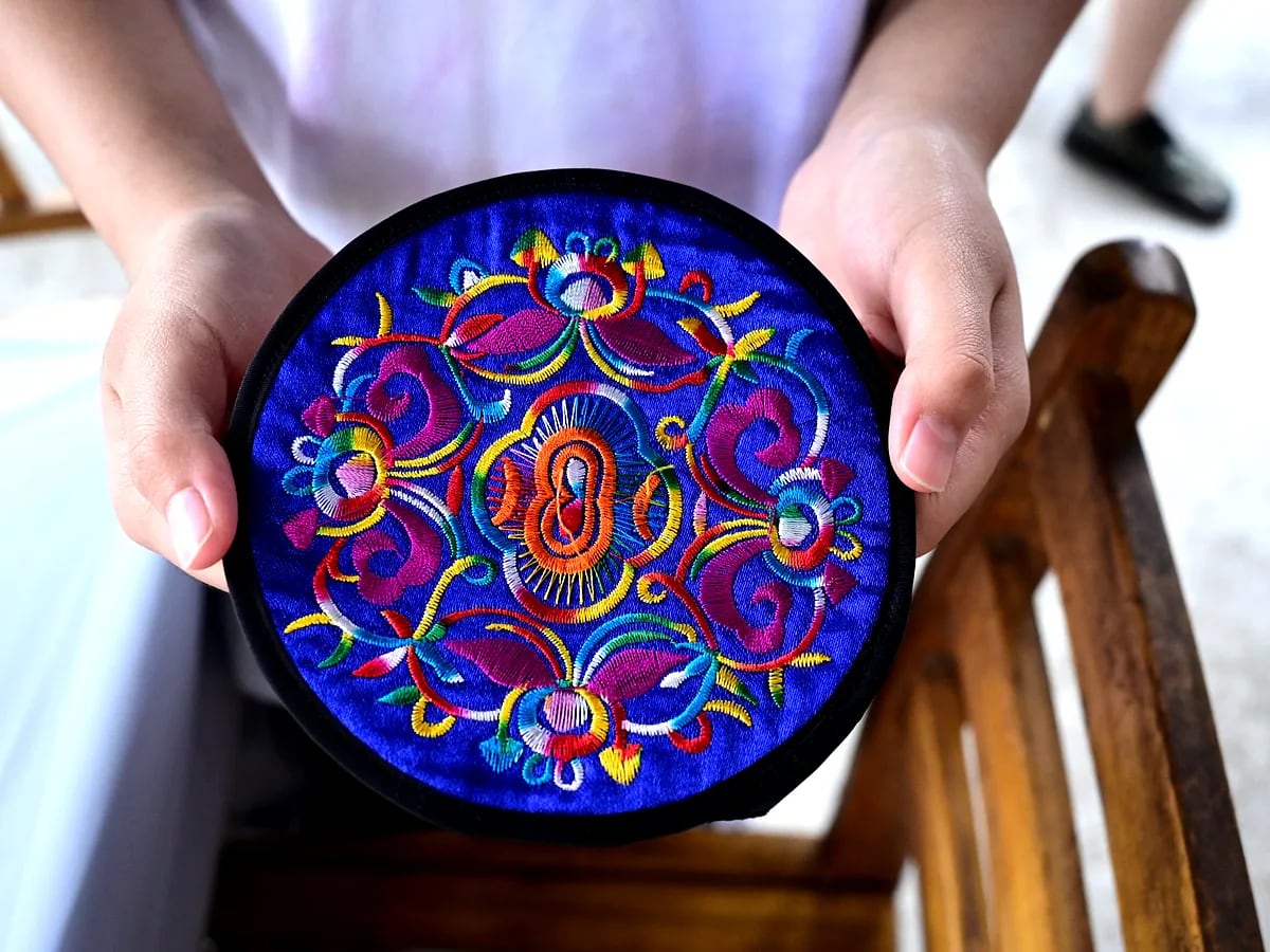 Hands holding a colorful embroidered textile during a Guangxi culture visit